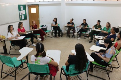 Para cego ver: Foto mostra diversas mulheres sentadas formando um círculo, conversando